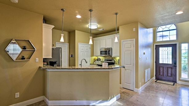 A kitchen with a central island, pendant lighting, and a view of the outside through a window. - Walk to Ocean: Lakefront Dickinson Stucco House! (Dickinson)