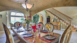 A dining area with a long table set for a meal, a staircase, and a view of the outdoors. - Extravagant 4,500 Sq Ft Home in Hill Country! (Spring Branch)