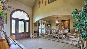 A spacious living room with a piano, dining area with chairs, and a large arched doorway. - Extravagant 4,500 Sq Ft Home in Hill Country! (Spring Branch)