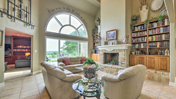 A spacious living room with a fireplace, a large bookshelf, and a comfortable seating area. - Extravagant 4,500 Sq Ft Home in Hill Country! (Spring Branch)