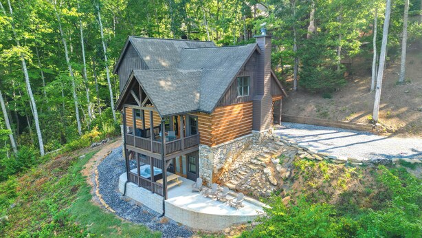 A cabin with a balcony, a stone wall, and a patio area. - Hot Tub + Pool Table: Cozy Franklin Cabin! (Franklin)