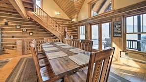 A spacious dining area with a long wooden table, multiple chairs, and a staircase leading to an upper level. - Hot Tub + Pool Table: Cozy Franklin Cabin! (Franklin)