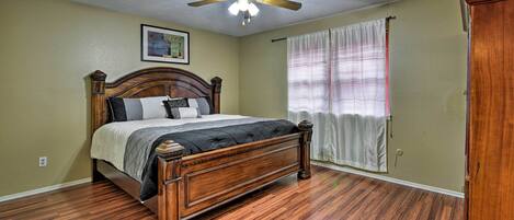 A bedroom with a wooden bed, a ceiling fan, and a window with curtains.