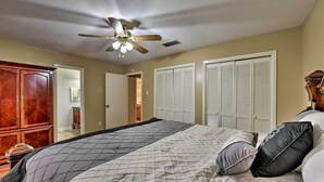 Une chambre à coucher avec un lit, un ventilateur de plafond et une armoire.