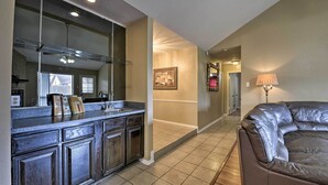 Une cuisine moderne avec des meubles de couleur bois foncé, une hotte de cuisine en acier inoxydable et un grand miroir au-dessus du plan de travail.
