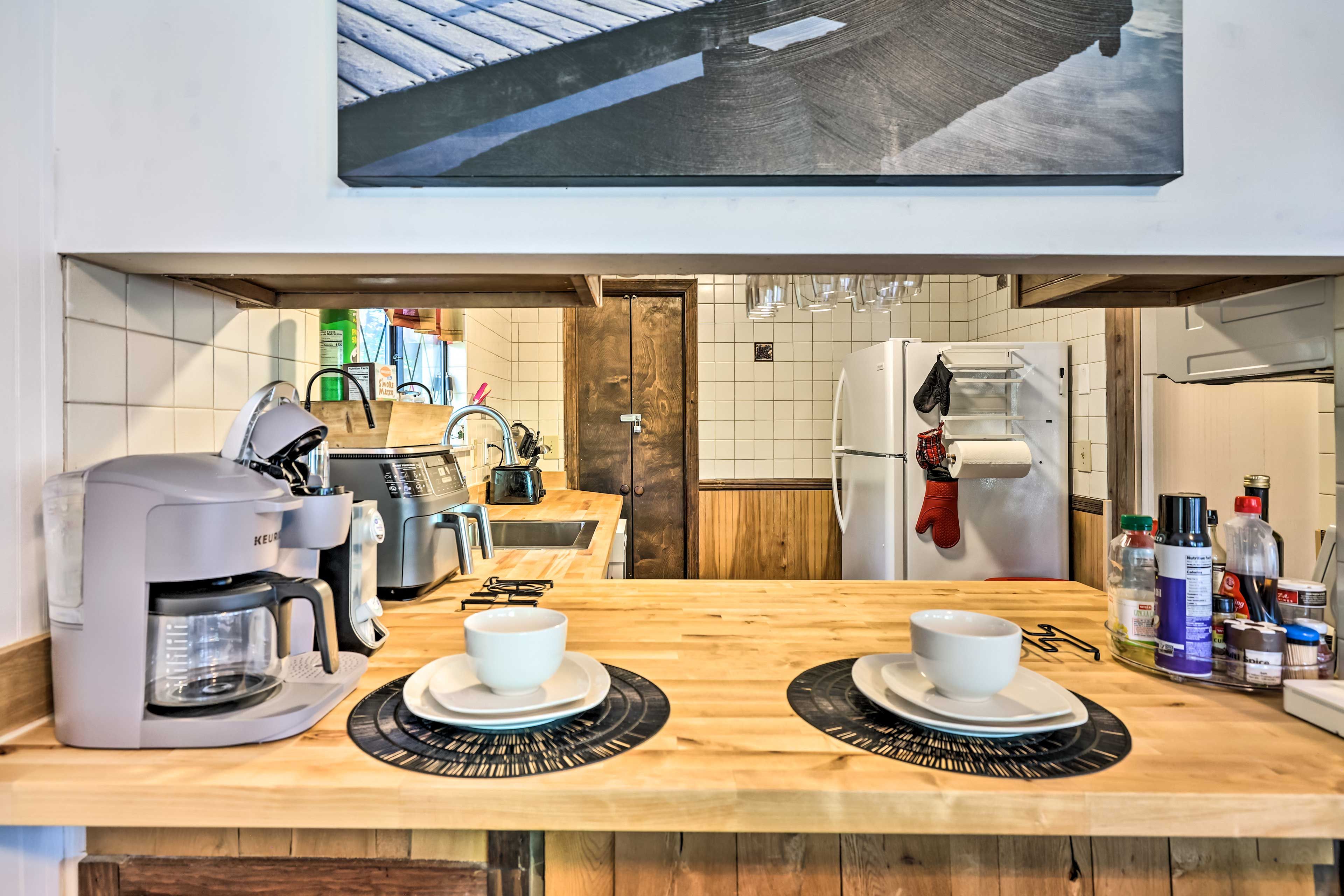A modern kitchen with a coffee maker, toaster, and refrigerator. There are two white cups on the counter.