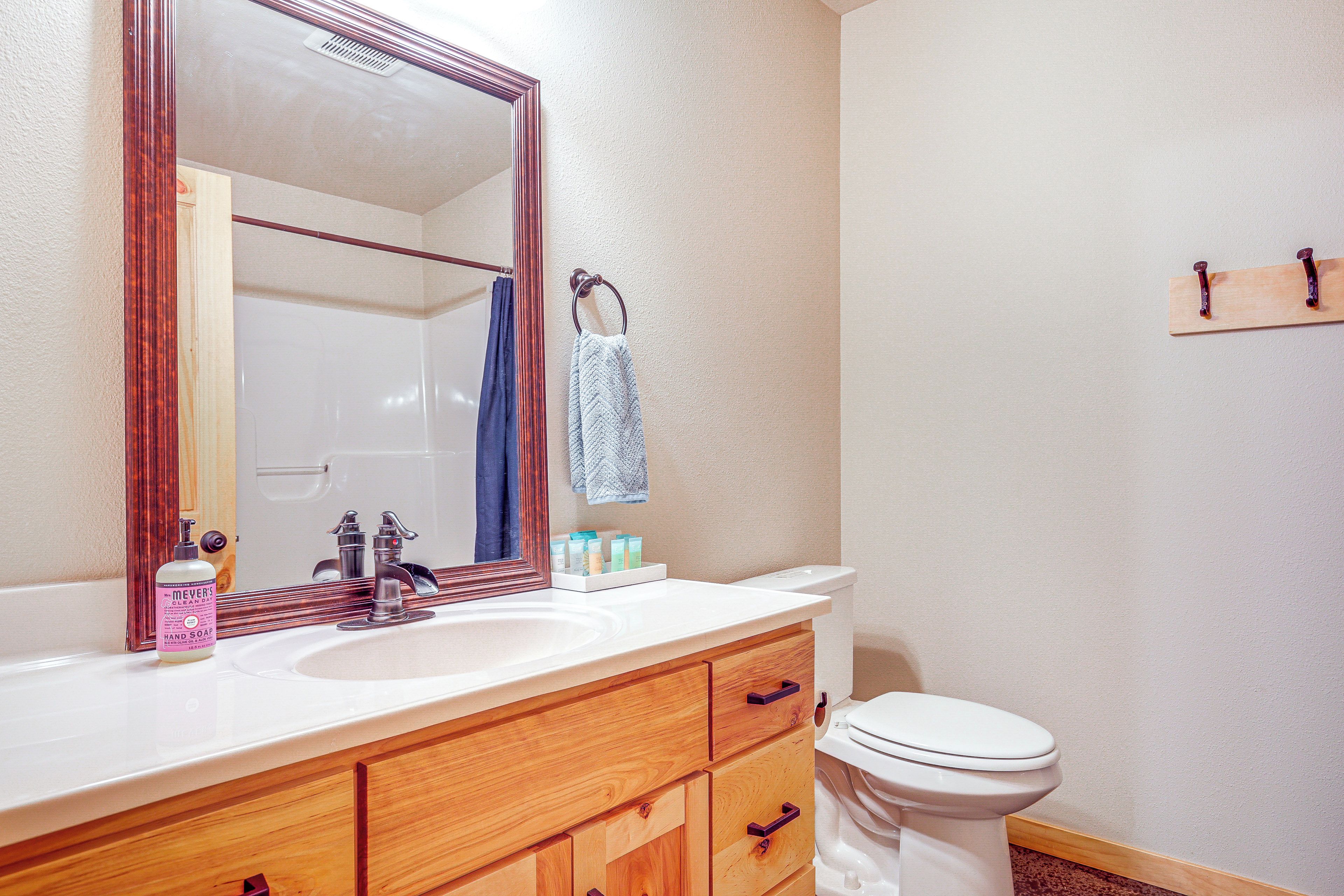 A bathroom with a wooden vanity, a large mirror, a white sink, and a toilet.
