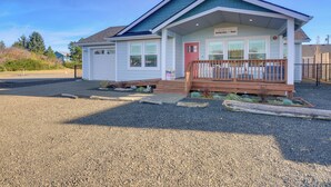 A single-story house with a red door, a porch with wooden railings, and a sign that reads "Saffire Store House." - Pet-friendly Retreat w/ Fenced Yard, Walk to Beach (Ocean Shores)