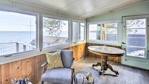 Ein gemütliches Zimmer mit einer holzgetäfelten Wand, einem runden Tisch mit Glasplatte und einem Stuhl mit Kissen.