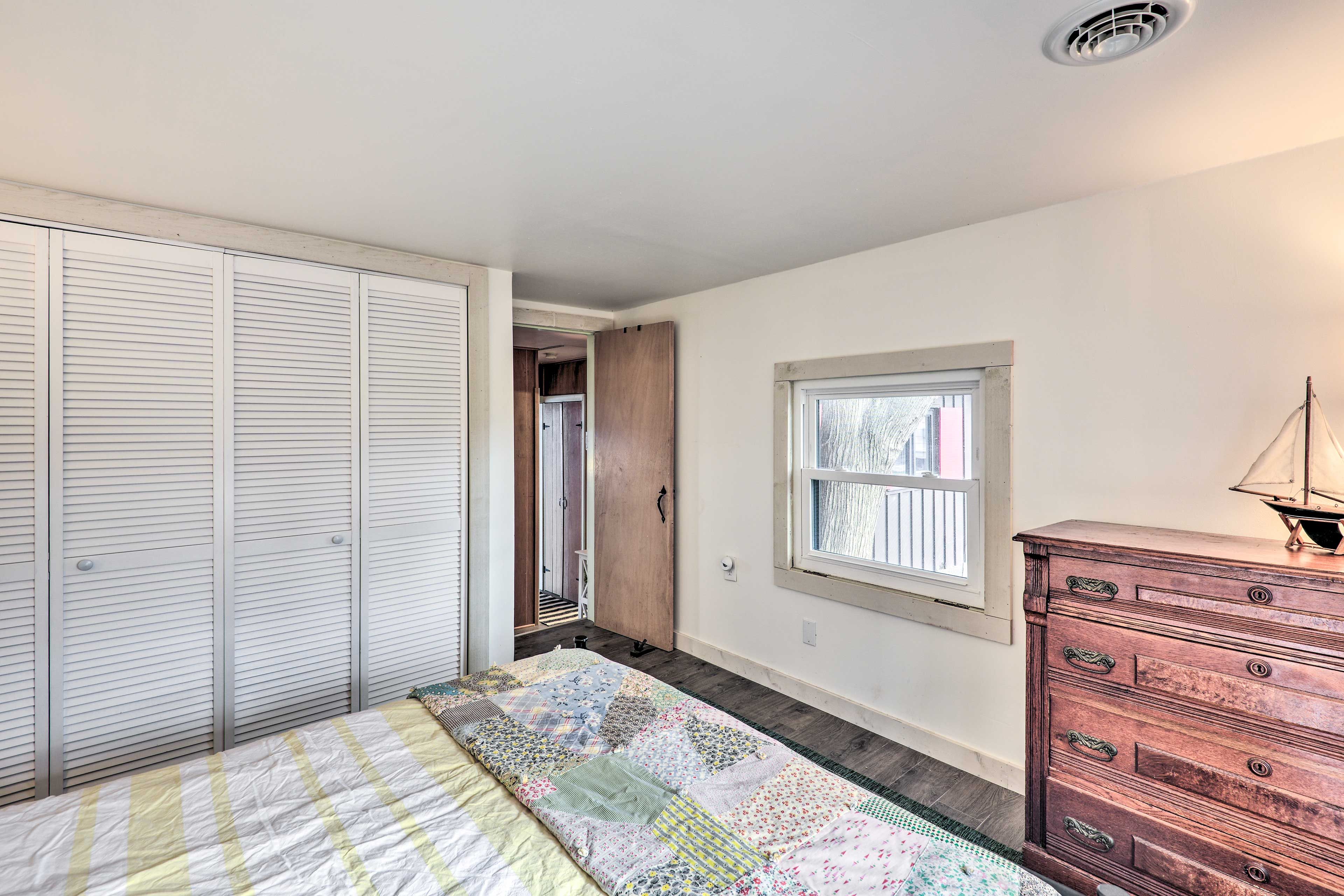 Une chambre à coucher avec un lit, une commode, une fenêtre et un placard.