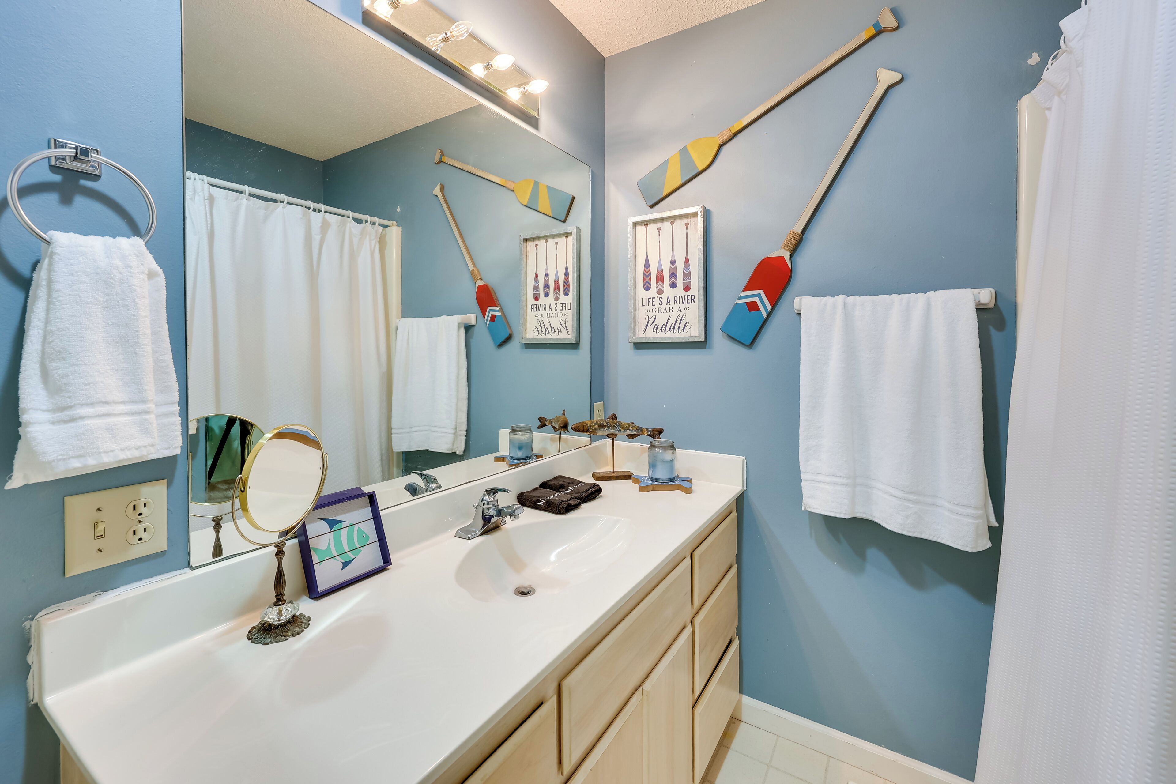 A bathroom with a white sink, mirror, and towel rack. There are two towels hanging on the rack.