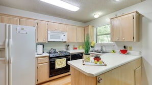 A modern kitchen with wooden cabinets, a white refrigerator, a microwave, and a stove. - Lakefront Home w/ Kayaks & Dock in Hot Springs! (Hot Springs)