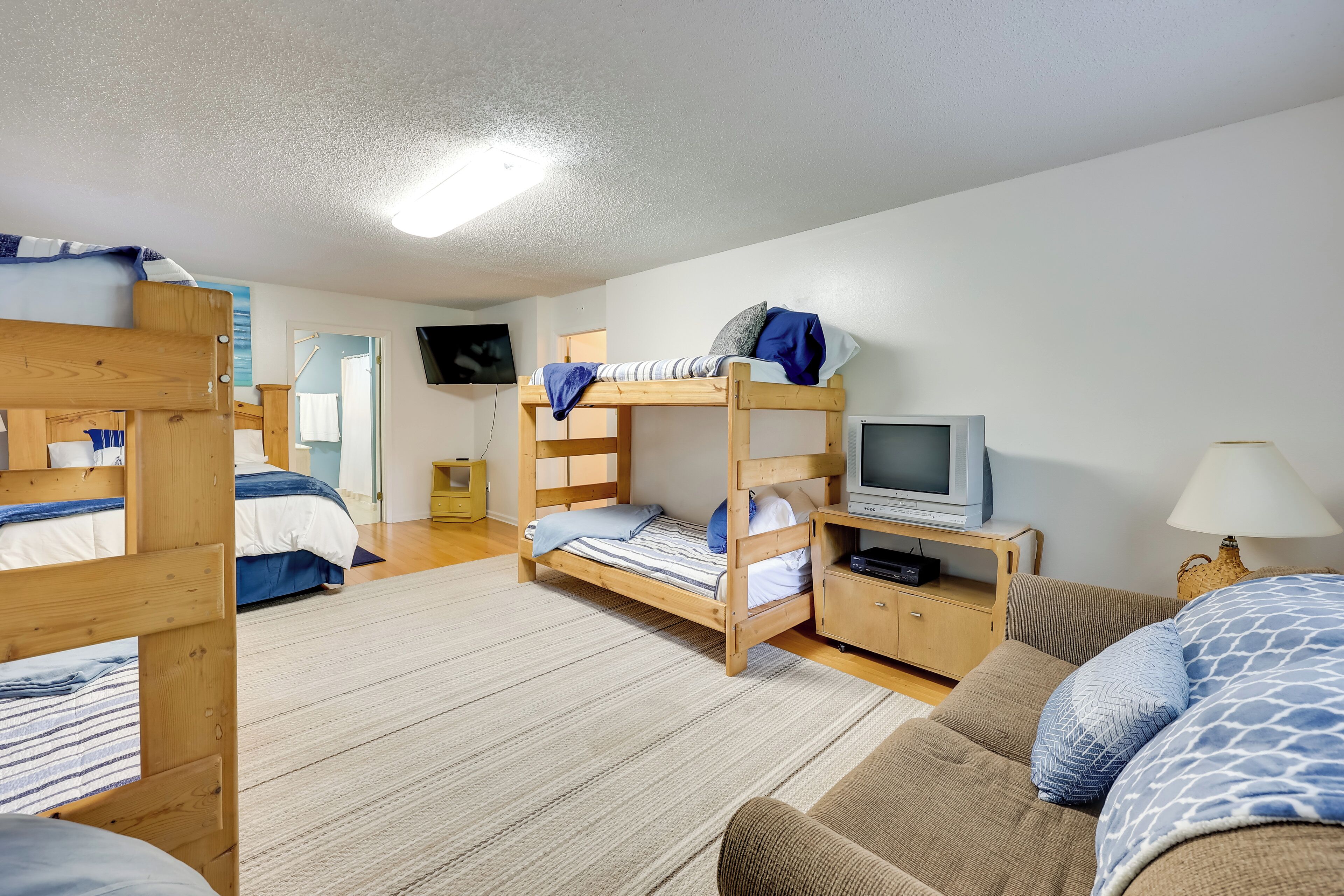 A room with bunk beds, a television, a sofa, and a lamp.
