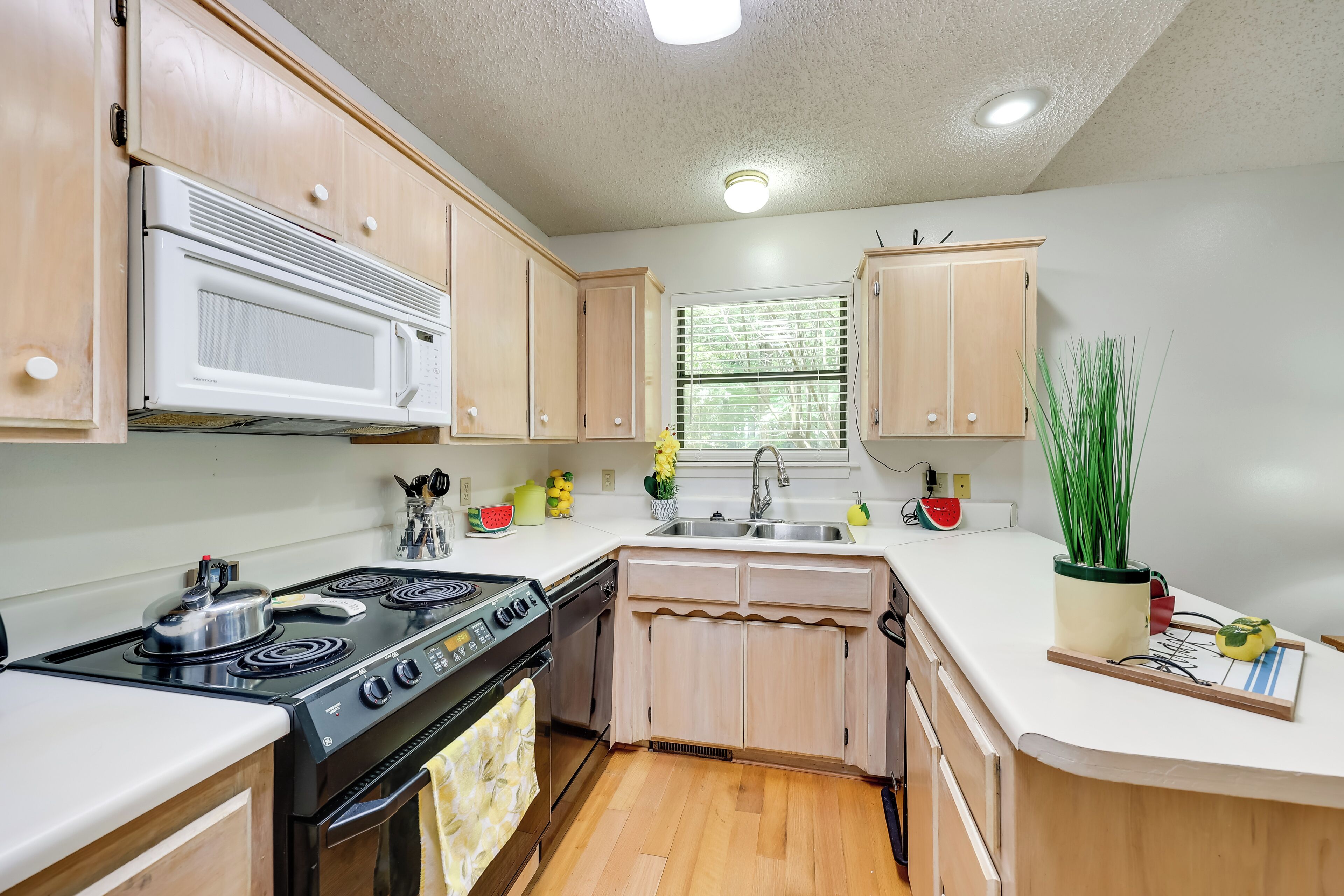 A compact kitchen with wooden cabinets, a built-in microwave, a stove, and a sink.