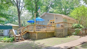 A two-story house with a wooden deck, a covered porch with blue umbrellas, and a flag. - Lakefront Home w/ Kayaks & Dock in Hot Springs! (Hot Springs)