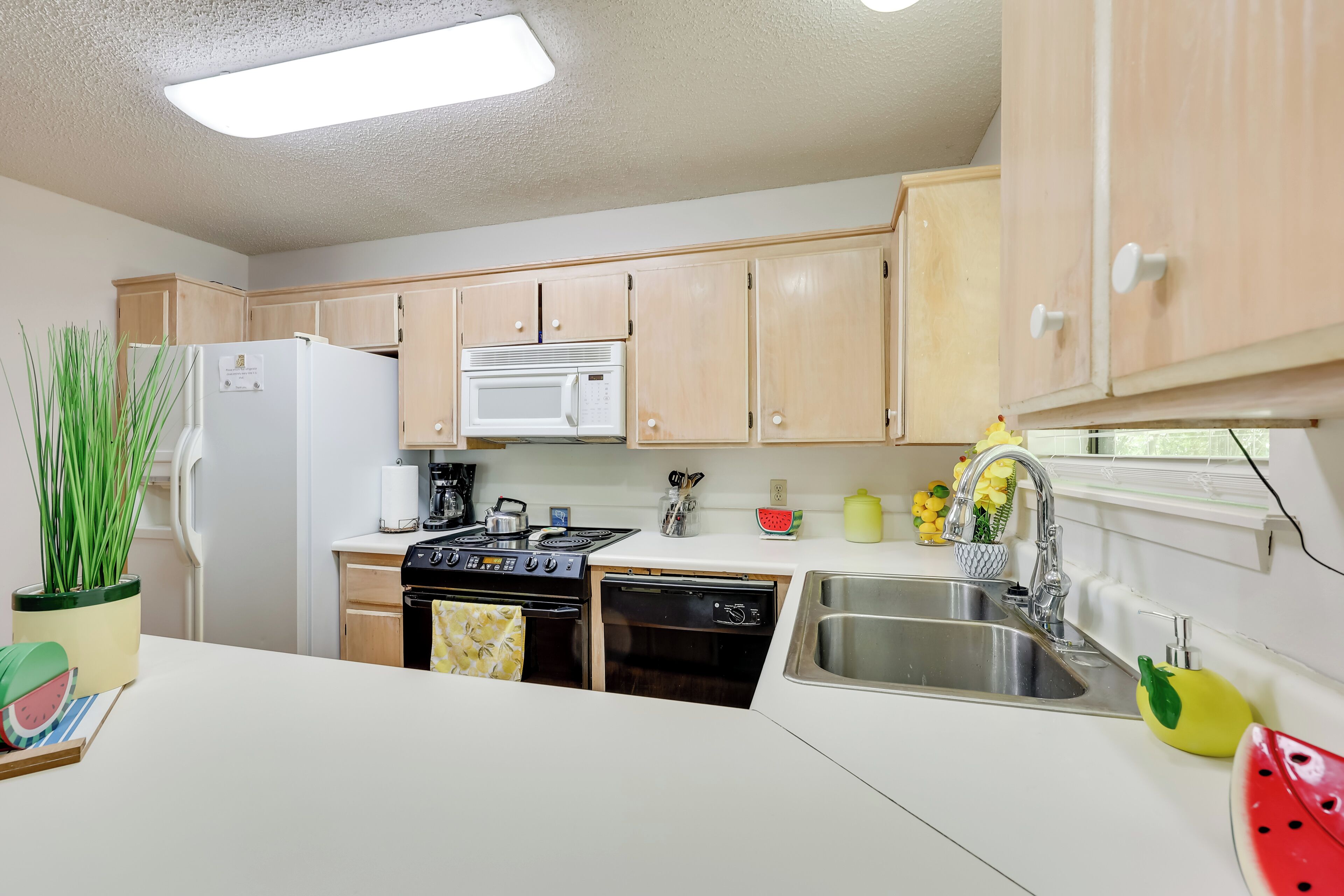 A kitchen with wooden cabinets, a refrigerator, a microwave, a stove, a dishwasher, and a sink.