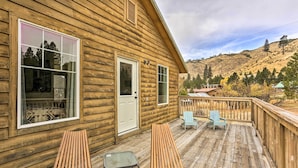 Une cabane en bois dotée d’une terrasse, de deux chaises longues et d’une petite table.