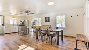 Une cuisine spacieuse équipée d’appareils électroménagers modernes, un coin repas avec une table et des chaises en bois, et un ventilateur de plafond.