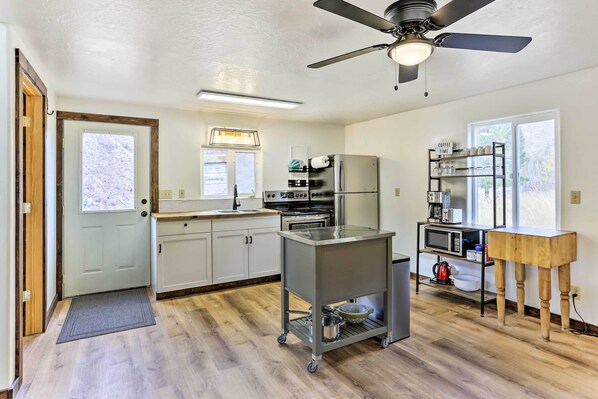 Una cocina moderna con ventilador de techo, electrodomésticos integrados y una estación para café.