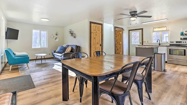 Un vaste espace de vie comprenant une table à manger en bois, un canapé et un téléviseur fixé au mur.