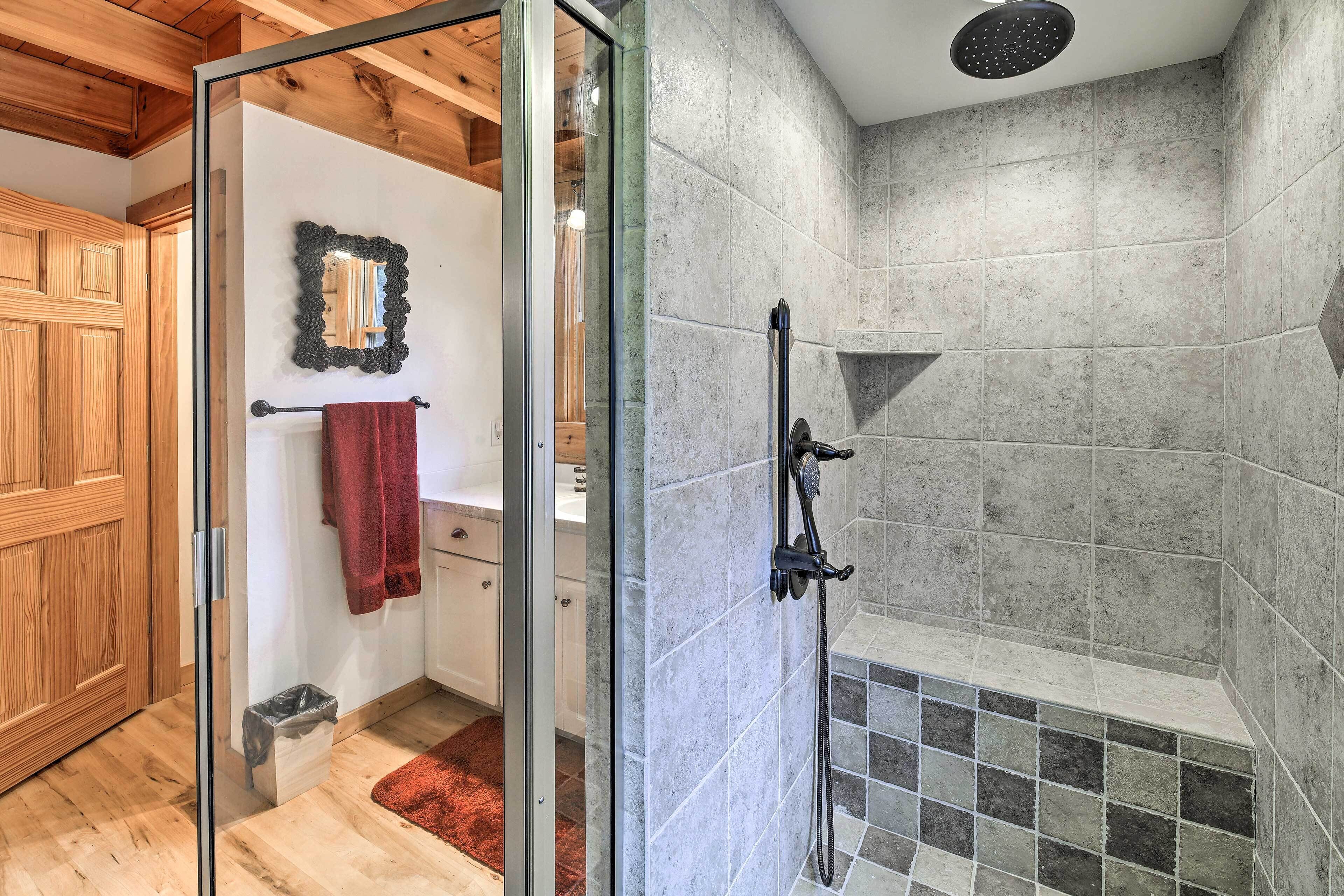 A shower area with tiled walls and a glass door leading to a bathroom.