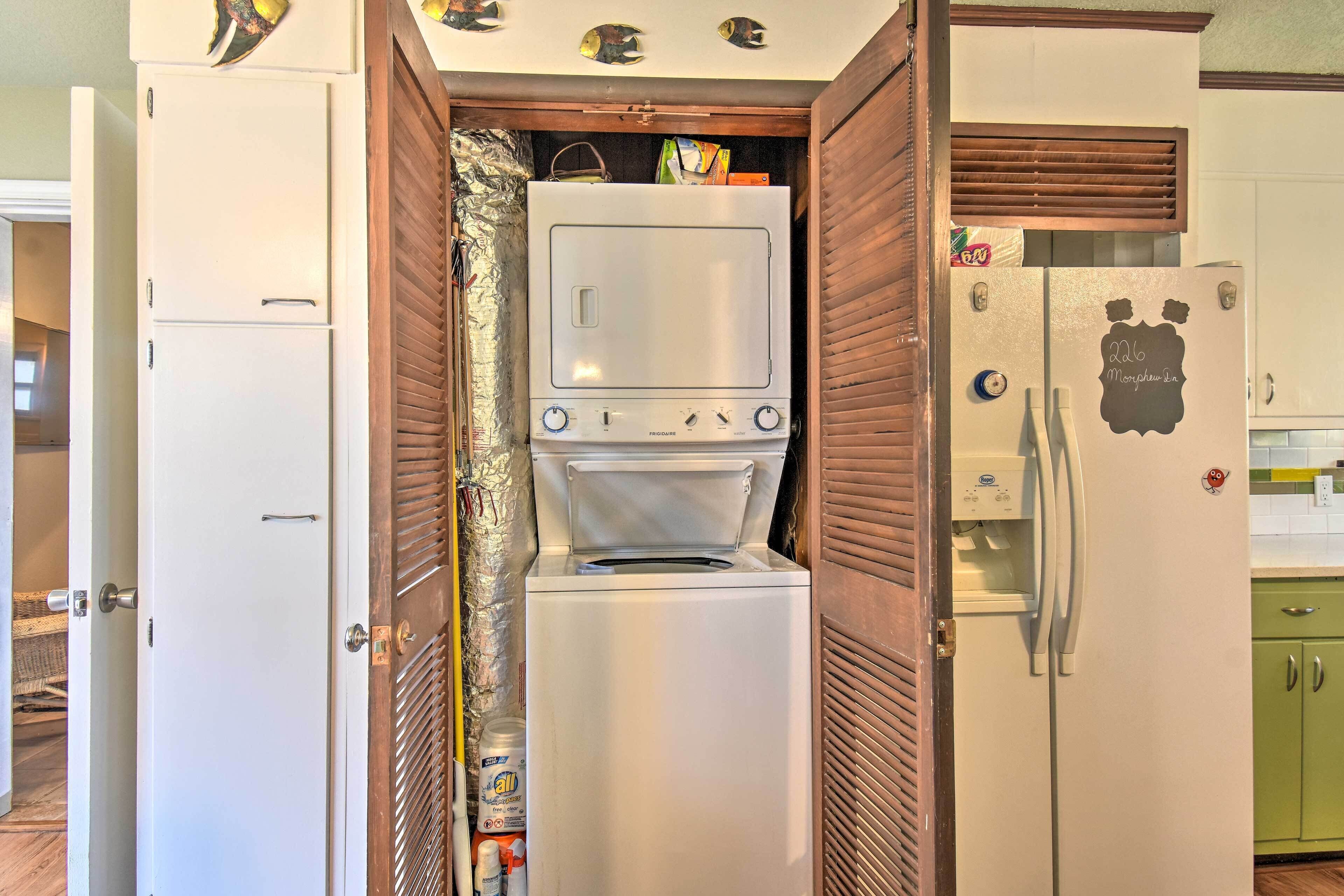 Una cocina compacta con lavadora y secadora integradas, un refrigerador y un armario verde.
