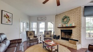 A living room with a fireplace, leather sofas, a coffee table, and a bookshelf.