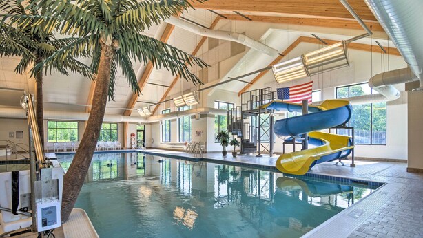 An indoor swimming pool with a slide, a palm tree, and an American flag.
