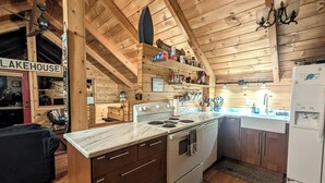 A wooden cabin interior with a kitchen featuring a stove, oven, and white refrigerator.