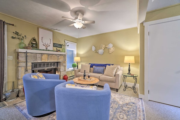 A living room with a fireplace, two blue armchairs, a beige sofa, and a ceiling fan. - Poconos Retreat By Jack Frost Wooded Escape (White Haven)