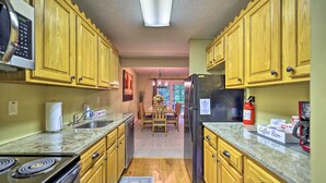 A kitchen with wooden cabinets, a refrigerator, a stove, and a coffee bar sign. - Mountain Retreat Near Jack Frost & Big Boulder (White Haven)