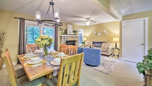 A dining area with a wooden table set for four, a chandelier, and a fireplace in the background. - Mountain Retreat Near Jack Frost & Big Boulder (White Haven)