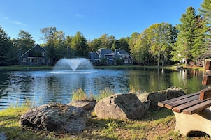 Un lago con una fuente, rodeado de casas y árboles.