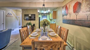 A dining room with a wooden table set for six, a chandelier, and a painting of trees on the wall. - Mountain Retreat Near Jack Frost & Big Boulder (White Haven)