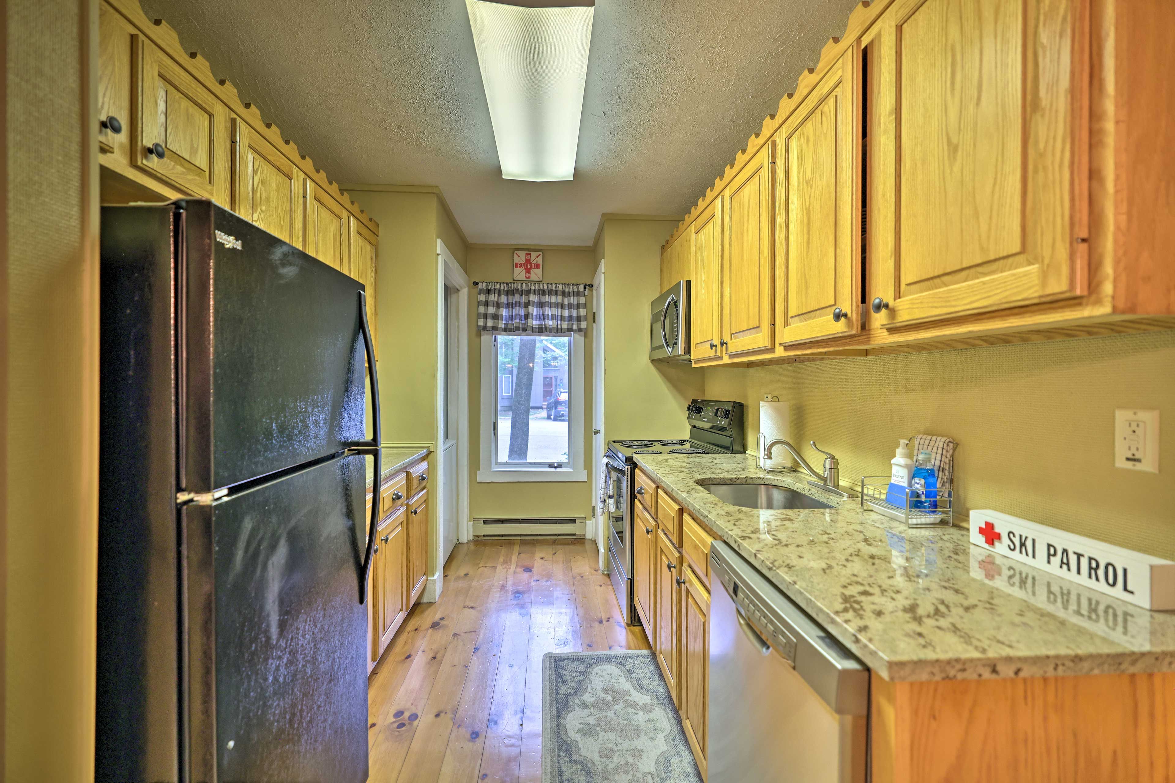 A kitchen with wooden cabinets, a black refrigerator, a microwave, a sink, and a sign that reads "SKI PATROL."