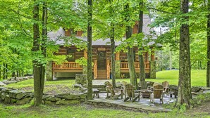 Eine Lodge mit einer Steinterrasse, Holzdeck und Sitzbereich im Freien, umgeben von Bäumen.