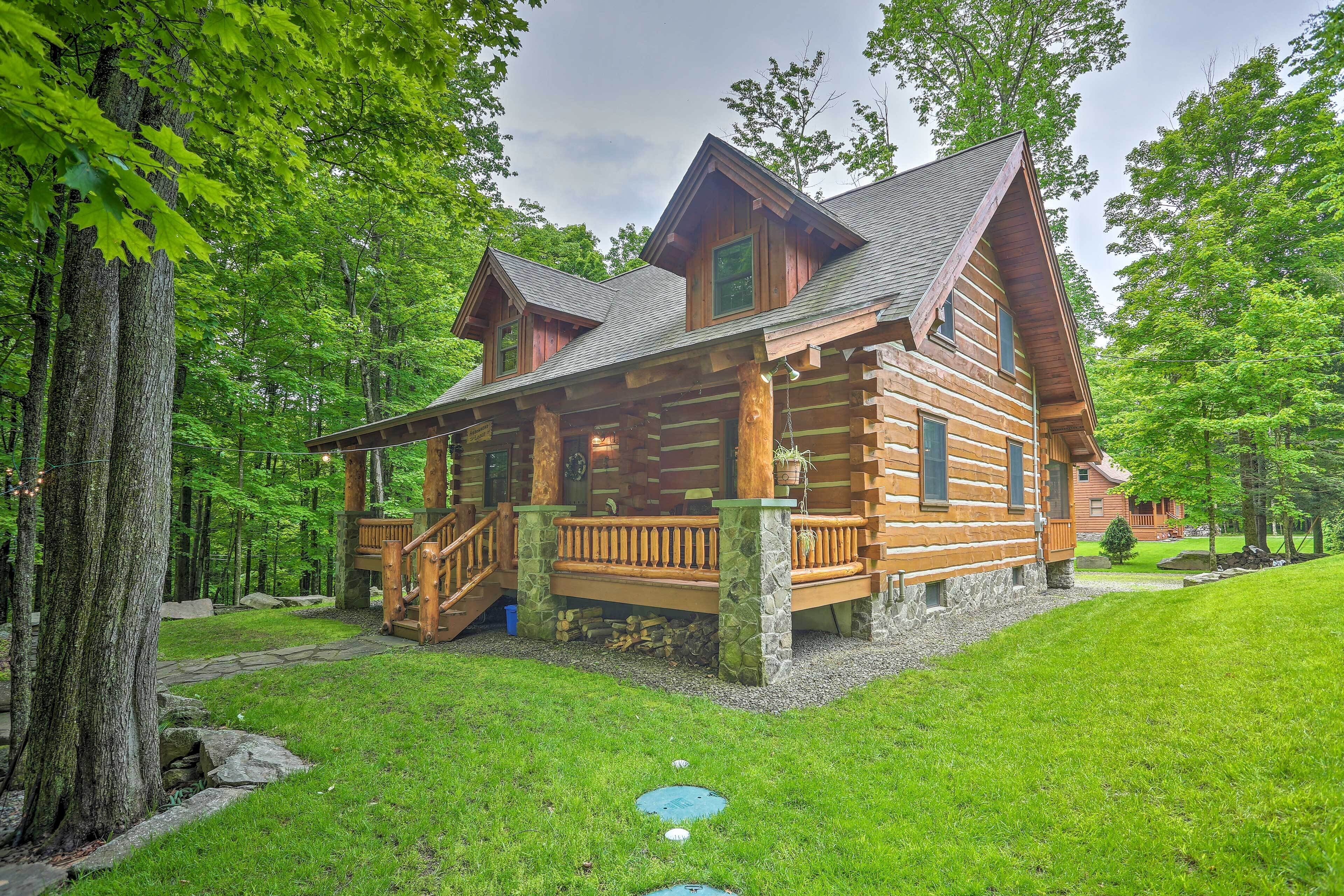 A log cabin with a stone foundation, wooden deck, and a staircase leading to the entrance.