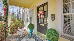 A porch with a rocking chair, a door with a wreath, and potted plants. - 'the Pink Azalea' - Tyler Home w/ Yard + Patio! (Tyler)