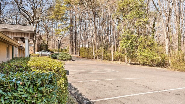 A parking lot with a building on the left and trees in the background. - Ideally Located & Updated Chapel Hill Apartment! (Chapel Hill)