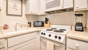 A kitchen with white cabinets, a microwave, a stove, a toaster, and a blender. - Ideally Located & Updated Chapel Hill Apartment! (Chapel Hill)