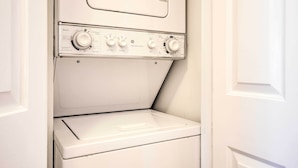 A white front-loading washing machine in a laundry room with a control panel featuring multiple dials and buttons. - Ideally Located & Updated Chapel Hill Apartment! (Chapel Hill)