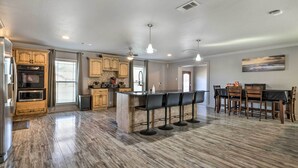 A spacious kitchen with wooden cabinets, a central island with bar stools, and a dining area with a table and chairs. - Inviting Gulfport Home w/ Private Pool & Yard (Gulfport)