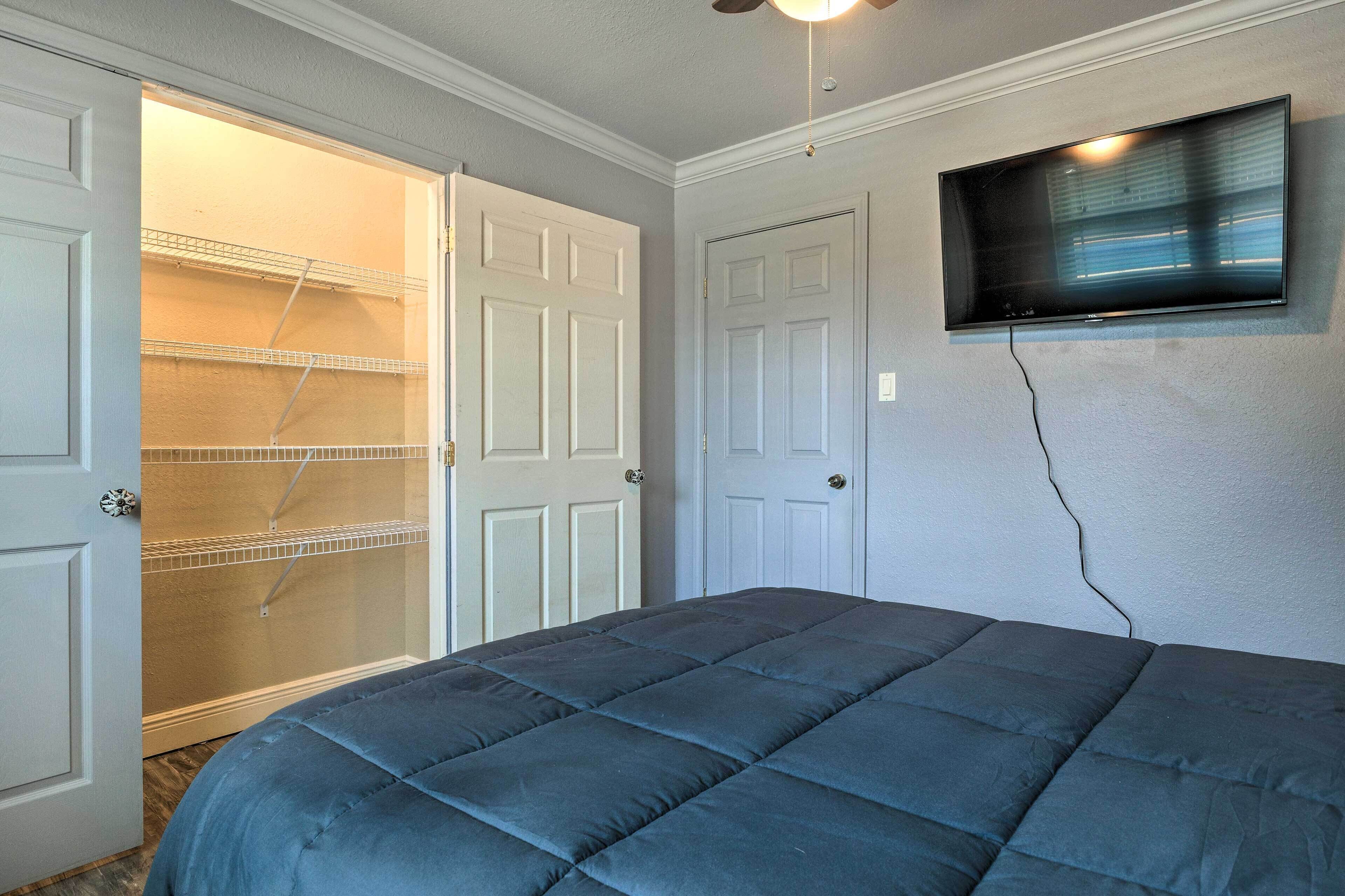 Une chambre à coucher avec un lit, un téléviseur fixé au mur et une armoire avec des étagères.