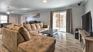 A spacious living room with a large sectional sofa, a coffee table, and a flat-screen TV on a wooden stand. - Inviting Gulfport Home w/ Private Pool & Yard (Gulfport)