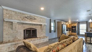 A spacious living room with a stone fireplace, a large sofa, and a kitchen area in the background. - Inviting Gulfport Home w/ Private Pool & Yard (Gulfport)