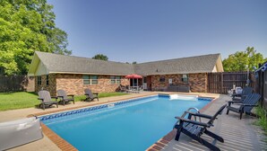 A backyard with a swimming pool, patio furniture, and a brick house. - Inviting Gulfport Home w/ Private Pool & Yard (Gulfport)