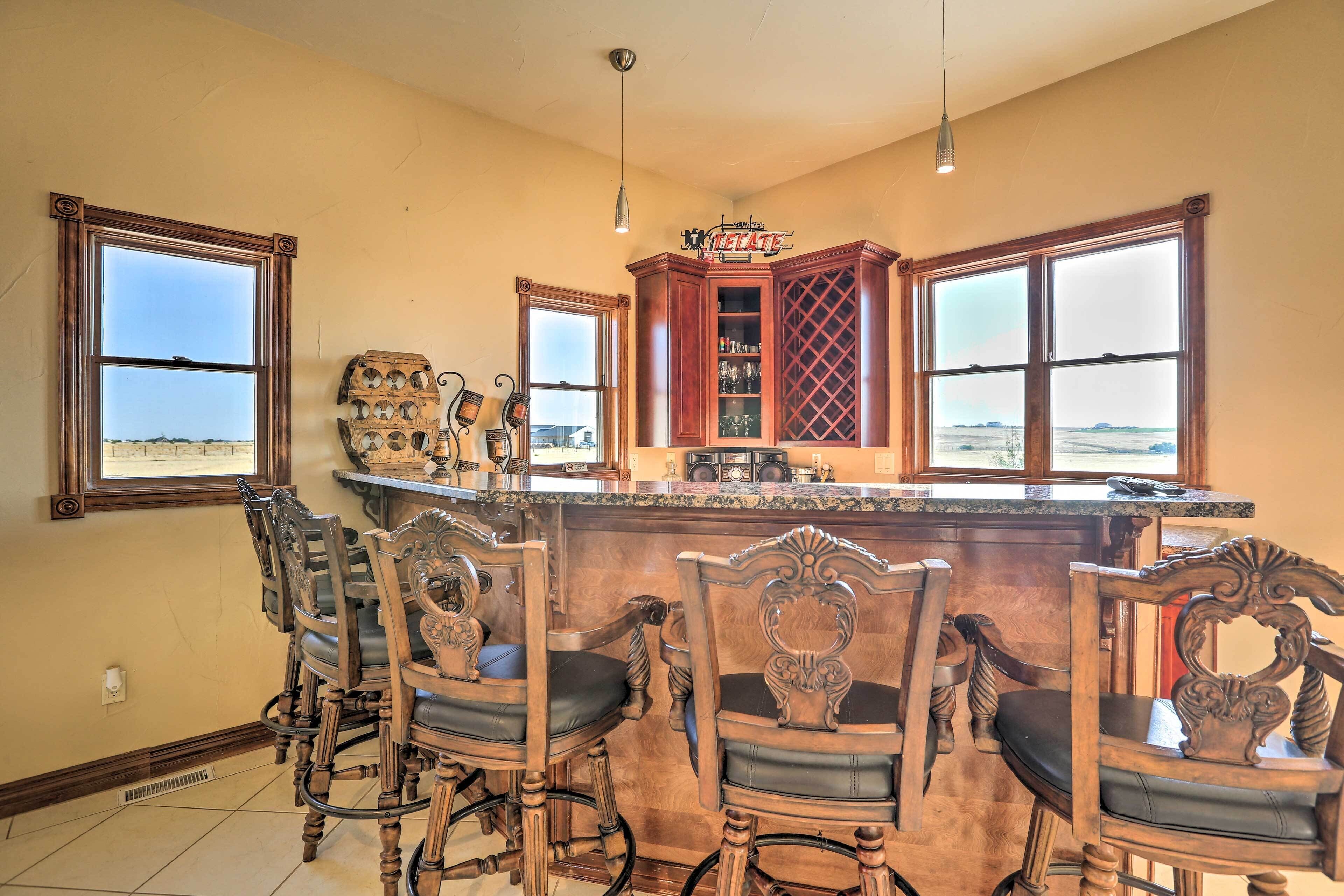 A bar area with a wooden bar counter, bar stools, and a wine rack.