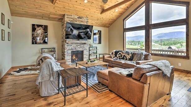 Un salón amplio con chimenea, sofás de cuero y un televisor grande.