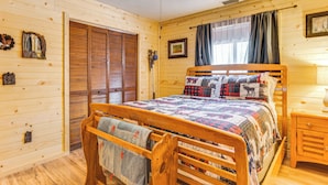 A wooden-paneled bedroom with a bed, a wooden chair, a nightstand, and a ceiling fan. - Murphy Cabin w/ Deck, Grill & Private Pond! (Murphy)