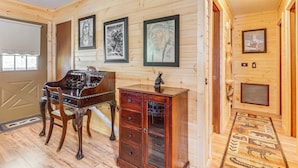 A wooden interior with a piano, a cabinet, and framed artwork on the walls. - Murphy Cabin w/ Deck, Grill & Private Pond! (Murphy)